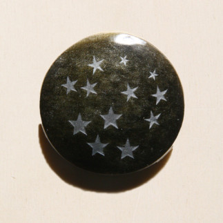 Cabochon en obsidienne dorée, avec des étoiles gravées sur la pierre.